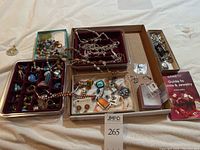 Overview of all jewelry pieces in trays and boxes including semi-precious beads, silver chains, pendants and charms