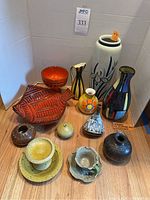 Overview of all twelve ceramic vases and dishes grouped on wooden surface