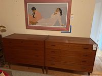Two teak dressers side by side under wall art