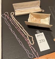 Five pearl necklaces displayed; including lavender, large seed, very large seed pearls, and classic 9 pearl necklace in cases