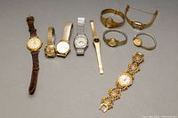 Top view of 10 ladies wristwatches arranged on a gray surface showing various bands and face styles