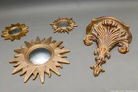 Set showing one large convex sunburst mirror, two smaller sunburst mirrors, and decorative wall sconce.