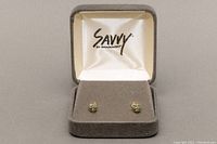 Pair of 14K gold small stud earrings with light blue aquamarine stones inside a Savvy by Swarovski grey jewelry box.