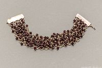 Full view of the sterling silver bracelet with garnet colored beads laid flat showing full bracelet length and details.
