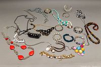 Full lot view of assorted costume necklaces and bangles showing layout and quantity