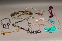All assorted costume necklaces displayed on flat surface showing variety of styles, colors, and materials.