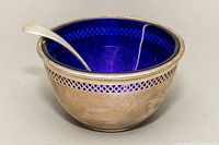 Silver sugar/condiment bowl with cobalt blue glass insert and silver spoon inside.