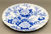 Top view of large scalloped ceramic serving platter with blue floral hand painted decoration.