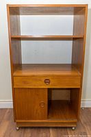 Front view showing two open shelves, drawer and lower compartment with sliding door open on right and dividers on left