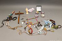 Overview of various religious items including crucifixes, rosaries, figurines, bracelets, and containers.