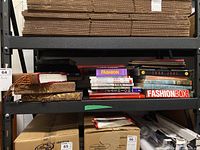Shelf filled with multiple books of assorted subjects and bindings, showing fashion books prominently.