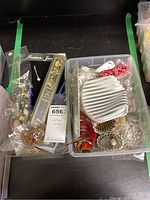 Two plastic boxes containing assorted costume jewelry pieces such as bracelets, necklaces, and earrings, some visible in plastic bags