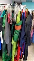 Rack of DC Comics adult costumes hanging on a rack with various colors and styles.