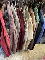 Side view of various ladies blazers hanging on hangers showing different fabrics and colors