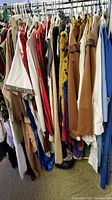 Side view of various medieval costume garments hanging on rack showing diverse colors and fabrics