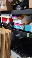 Shelving unit containing cardboard frames, photo albums, and reams of paper.