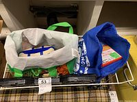 Overview photo showing multiple bags containing PlayStation 2 console, Wii games and accessories, and a laptop cooler.