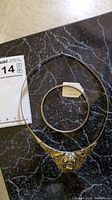 Full view of the torque necklace with the Mexican silver bracelet beside it, on a dark surface.