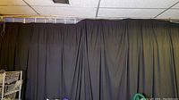 Large black theater drape covering a wall on a curtain rod or track.