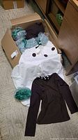 Box with green wigs, brown shirt, white pants visible
