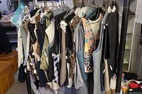 Photo showing a rack with approximately 15 assorted suit vests of various styles and colors, hung on hangers.