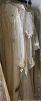 Photo of several vintage wedding dresses hanging, showing puff sleeves and lace cuffs