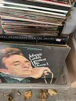 Photo of a box filled with assorted vintage vinyl records showing the front cover of 'Johnny Cash's Greatest Hits Volume 1' prominently.