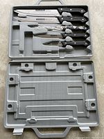 Full view of five Koch Messer knives with black handles in gray molded plastic carrying case.