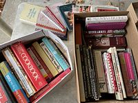 Two boxes filled with assorted cookbooks, primarily hardcover with some visibly titled Betty Crocker and other brands.