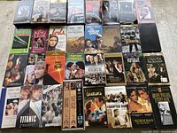 Top-down photo of 43 assorted classic and vintage VHS tapes, many with original covers, some factory sealed while a few cases are damaged.