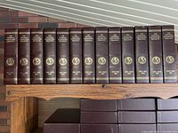 13 brown hard slip cases arranged on wooden shelf, each labeled with year range from 1990 to 1998 for National Geographic magazines.