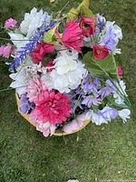 Large basket filled with various colors of artificial flowers including pink, white, purple, and red with green leaves.