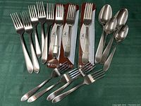 Six used forks with traditional tine structure, four forks in original sealed packaging, four used spoons with oval bowls.