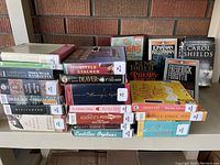 Photo showing a stack of various audiobooks on CD mostly library discards with visible labels, showing some wear and used condition.