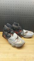 Pair of used Nike LeBron James men's basketball shoes size 11.5 in gray, black with orange accents, photographed from a side angle showing wear and general condition.