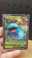 Photo of a single Pokemon Venusaur V trading card held against a neutral background.