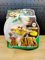 Front view of sealed Baby Sinclair toy packaging with visible wear and tear on the cardboard backing