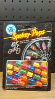 Front view of original sealed blister pack with colorful plastic soda can shaped spoke caps attached.