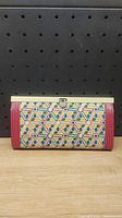 Front view of women's wallet clutch showing colorful geometric pattern and metal frame clasp.
