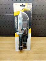 Front view of new Yukon Gear survival knife in packaging showing knife with black handle and protective sheath.