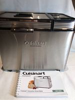 Front view of Cuisinart CBK-200C convection bread maker with instruction and recipe booklet beside it.