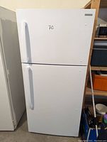 Closed front view of white Insignia refrigerator with freezer on top showing dual doors and curved handles.