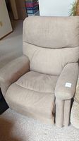Front view of one beige La-Z-Boy recliner showing cushioned armrests and backrest, fabric in worn but good condition.