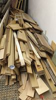 Long pile of assorted wood boards, dimensional lumber, and live edge pieces stacked against a wall