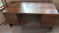 Full view of the wooden desk showing smooth rectangular top and drawer configuration.