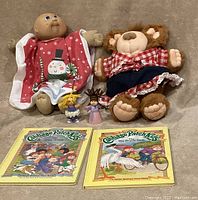 Full lot showing two dolls, two yarn-haired figurines, and two Cabbage Patch Kids books