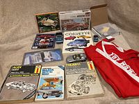 Full overview of lot with manuals, model kits, diecast cars, book, jacket, and trim