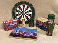 Overview of the lot showing the dartboard at back, four collector tins and the Pickup Sticks game in front