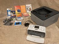 Lot overview photo showing HP Photosmart A716 printer, Samsung ML-2851ND laser printer, various ink cartridges, software boxes, and cables.