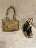 Full view of American West hand embossed leather purse and Cromia mixed leather and cowhide purse from side angle